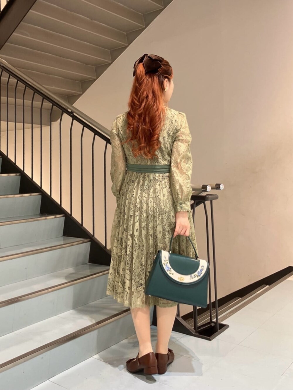 ブルー系のハンドバッグ、ブラウン系のバレエシューズ、グリーン系のドレスを着用したレディースの冬コーディネートの4枚目の写真