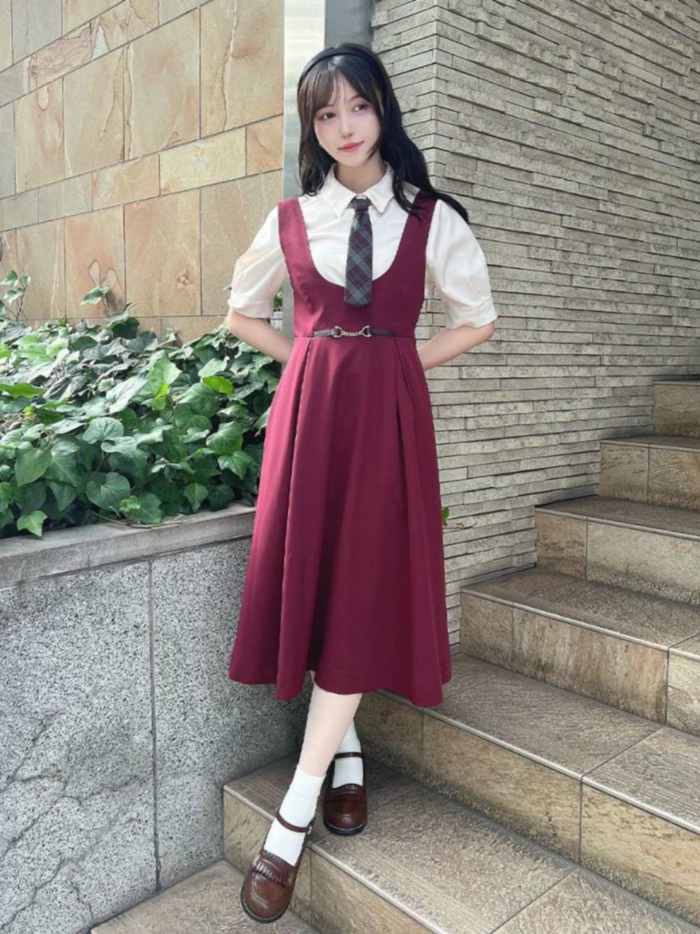 ブラウン系のローファー、レッド系のジャンパースカート、ホワイト系のTシャツ/カットソーを着用したレディースの秋コーディネートの2枚目の写真