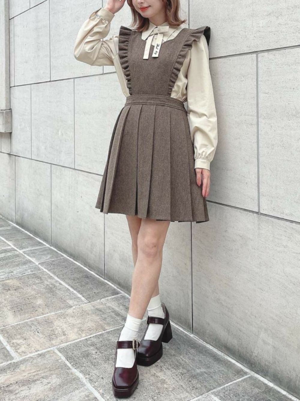 ブラック系のパンプス、ブラウン系のジャンパースカート、ベージュ系のシャツ/ブラウスを着用したレディースの秋コーディネートの2枚目の写真