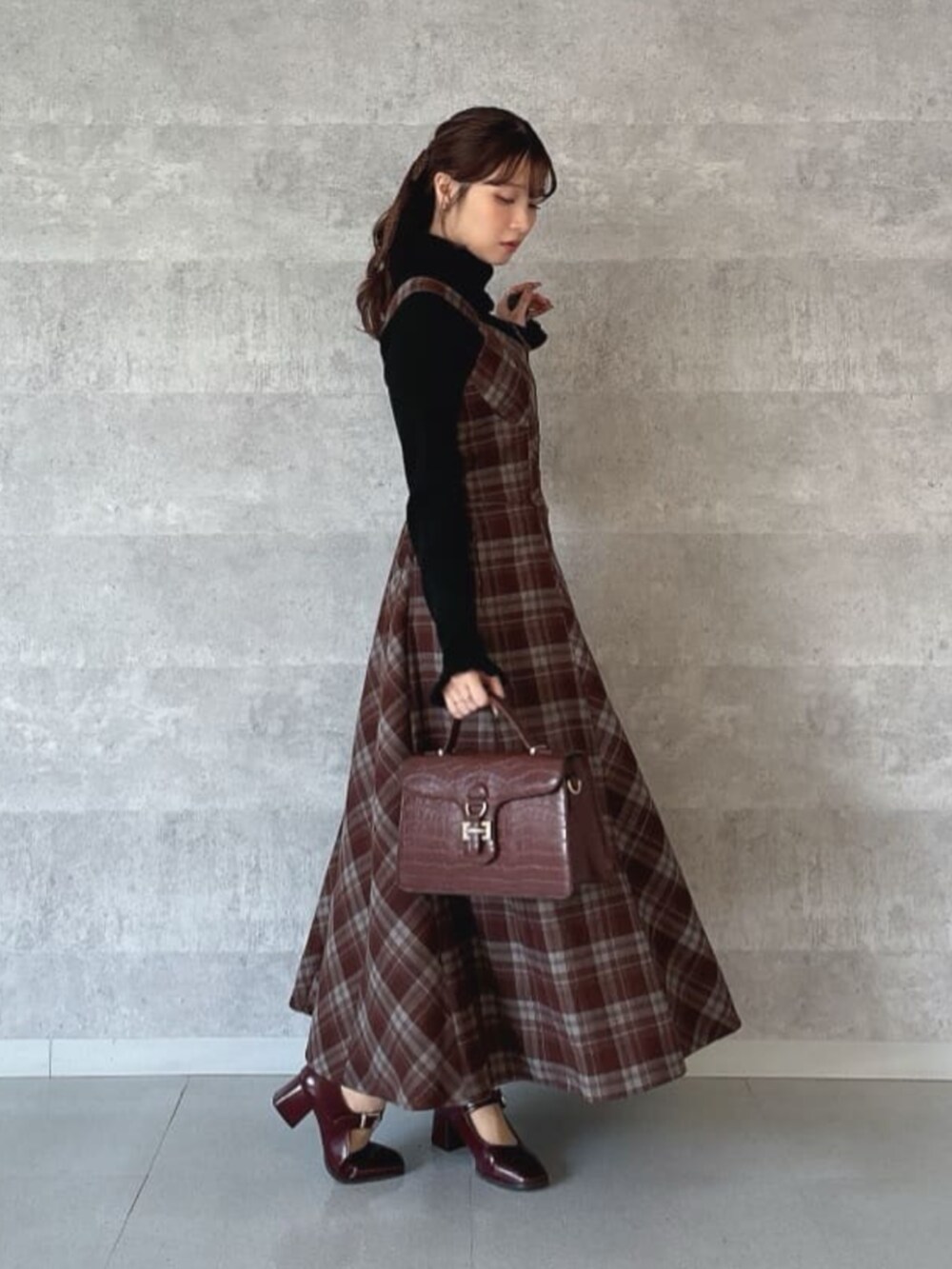 レッド系のパンプス、イエロー系のハンドバッグ、ブラック系のニット/セーターを着用したレディースの秋コーディネートの2枚目の写真