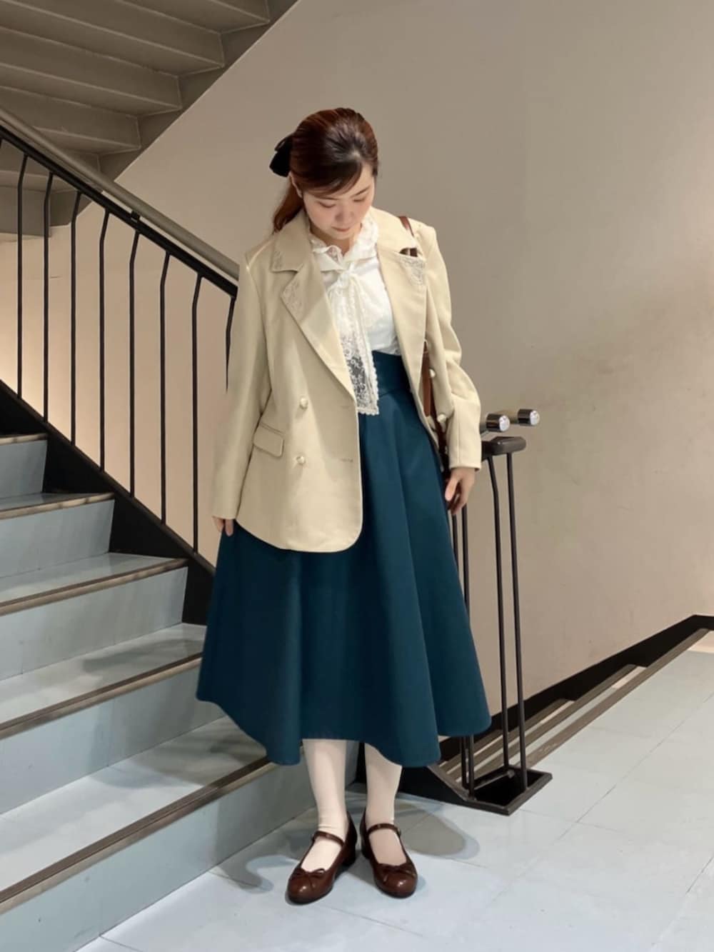 ブラウン系のパンプス、ホワイト系のシャツ/ブラウス、ブラウン系のショルダーバッグを着用したレディースの冬コーディネートの2枚目の写真