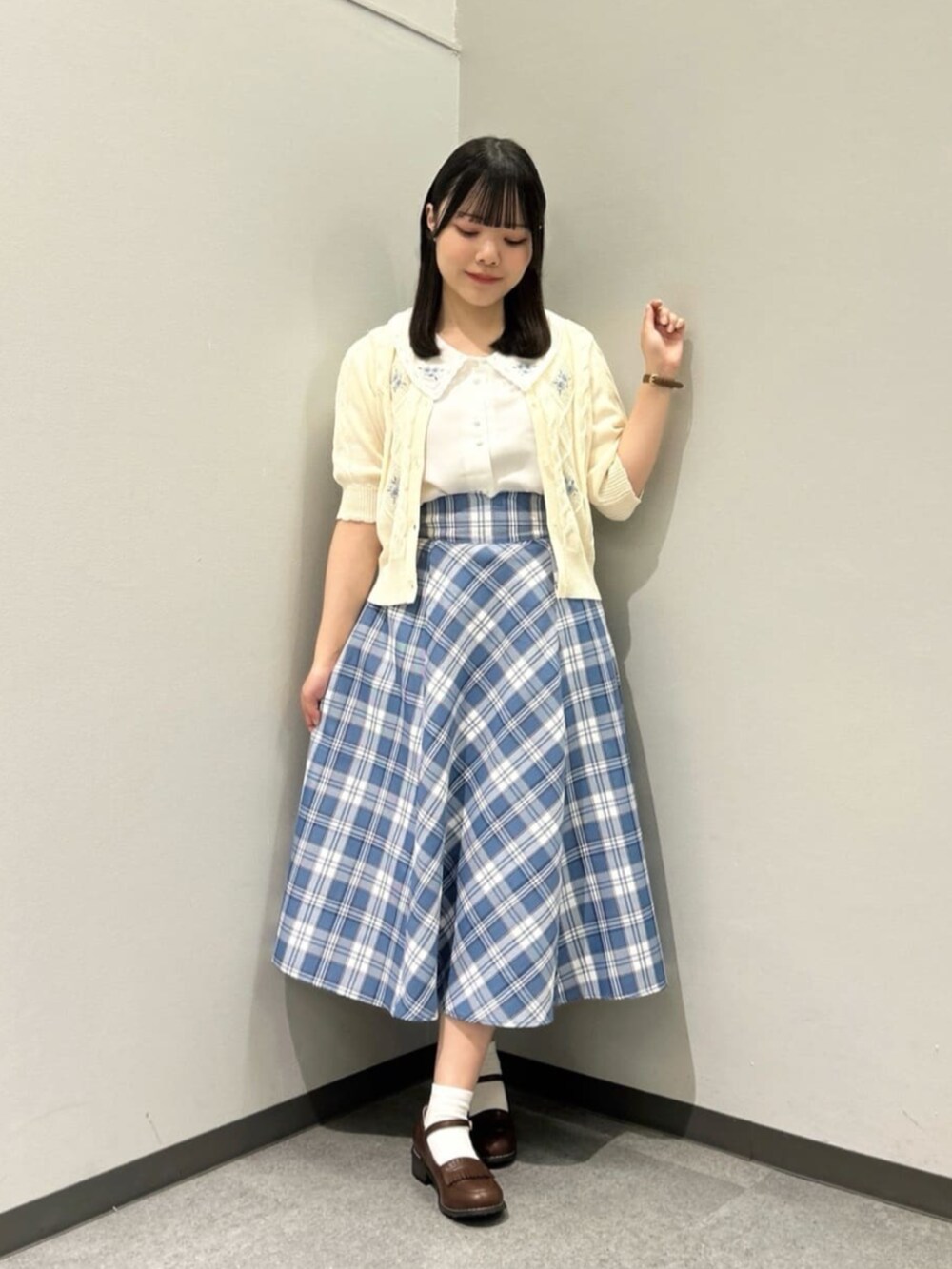 ベージュ系のハンドバッグ、ブラウン系のローファー、ホワイト系のカーディガン/ボレロを着用したレディースの春コーディネートの2枚目の写真