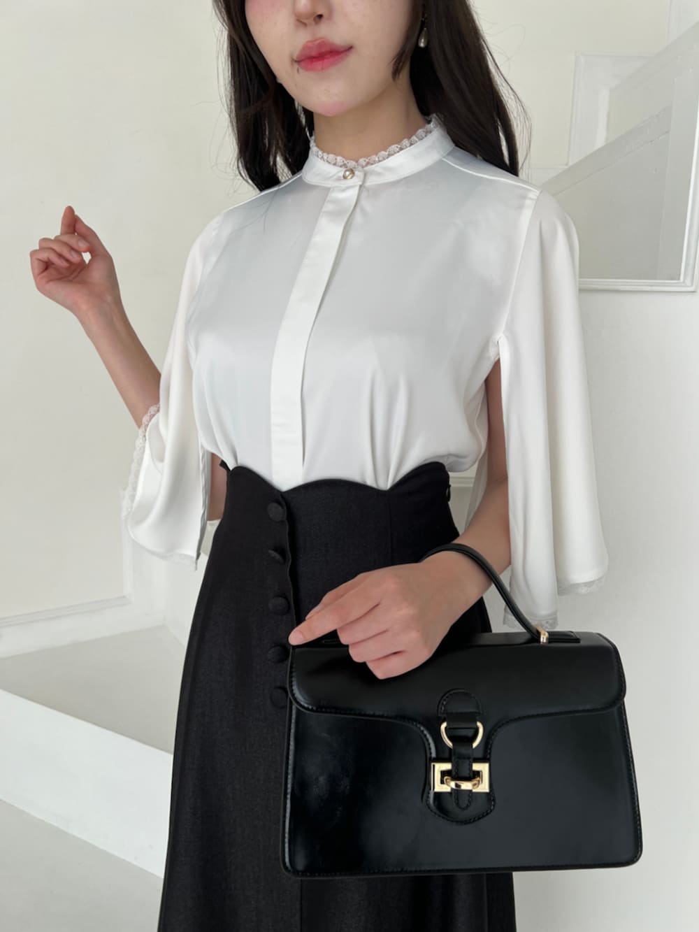 ブラック系のハンドバッグ、ブラック系のデニムスカート、ホワイト系のシャツ/ブラウスを着用したレディースの夏コーディネートの4枚目の写真