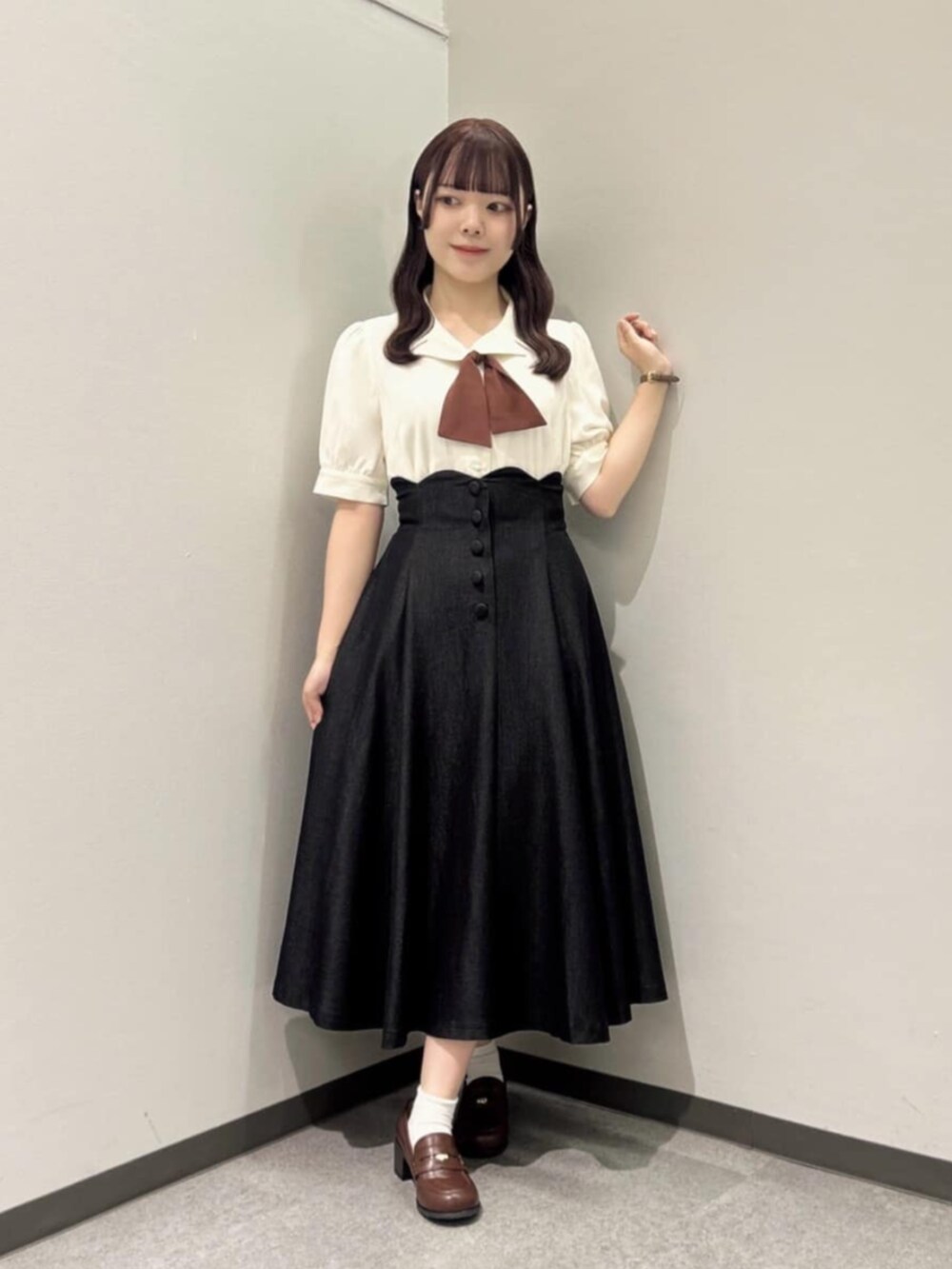 ブラウン系のローファー、ブラック系のデニムスカート、ホワイト系のシャツ/ブラウスを着用したレディースの秋コーディネートの2枚目の写真