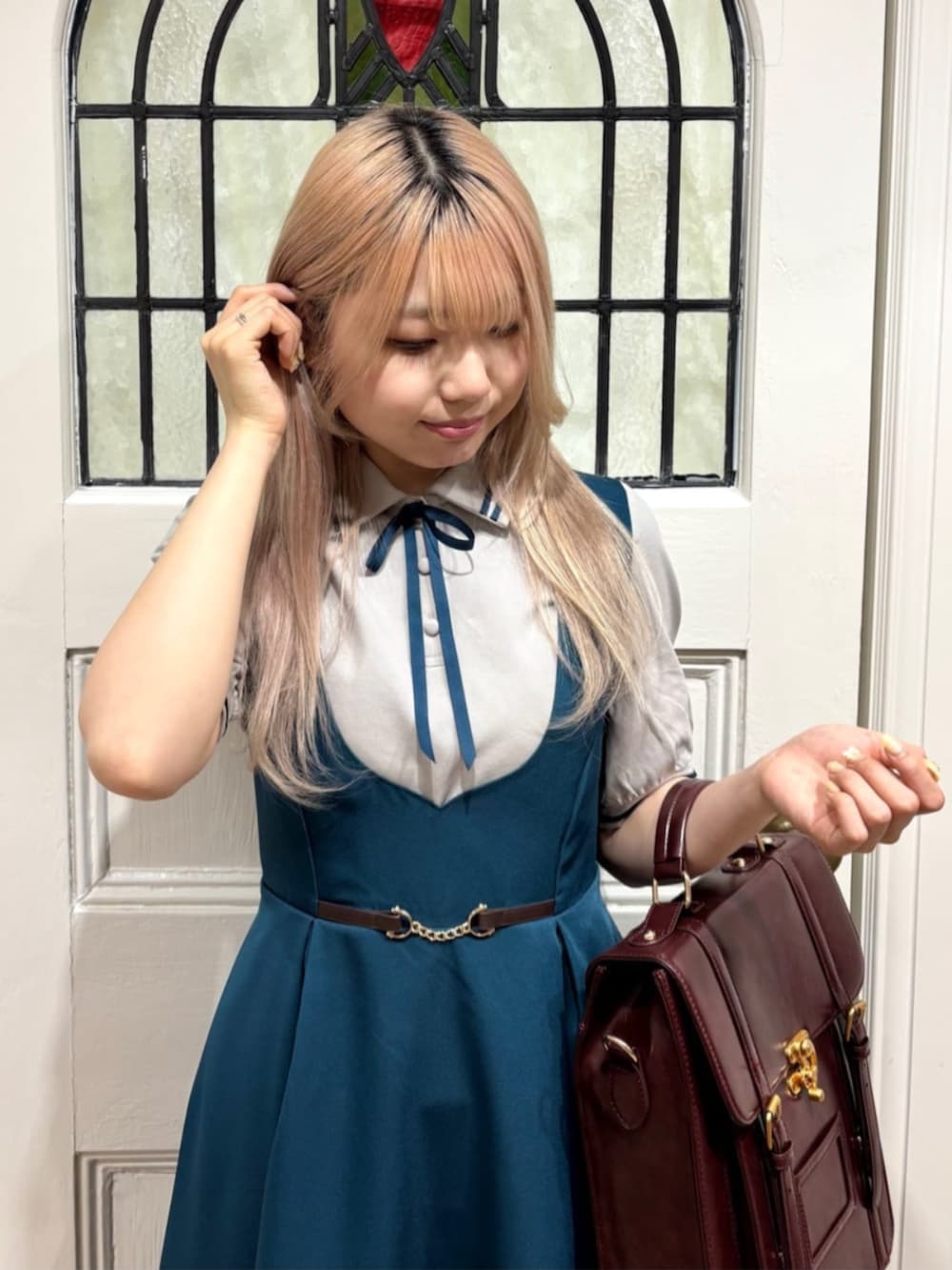 ブラウン系のハンドバッグ、ブラウン系のローファー、ブルー系のジャンパースカートを着用したレディースの夏コーディネートの3枚目の写真