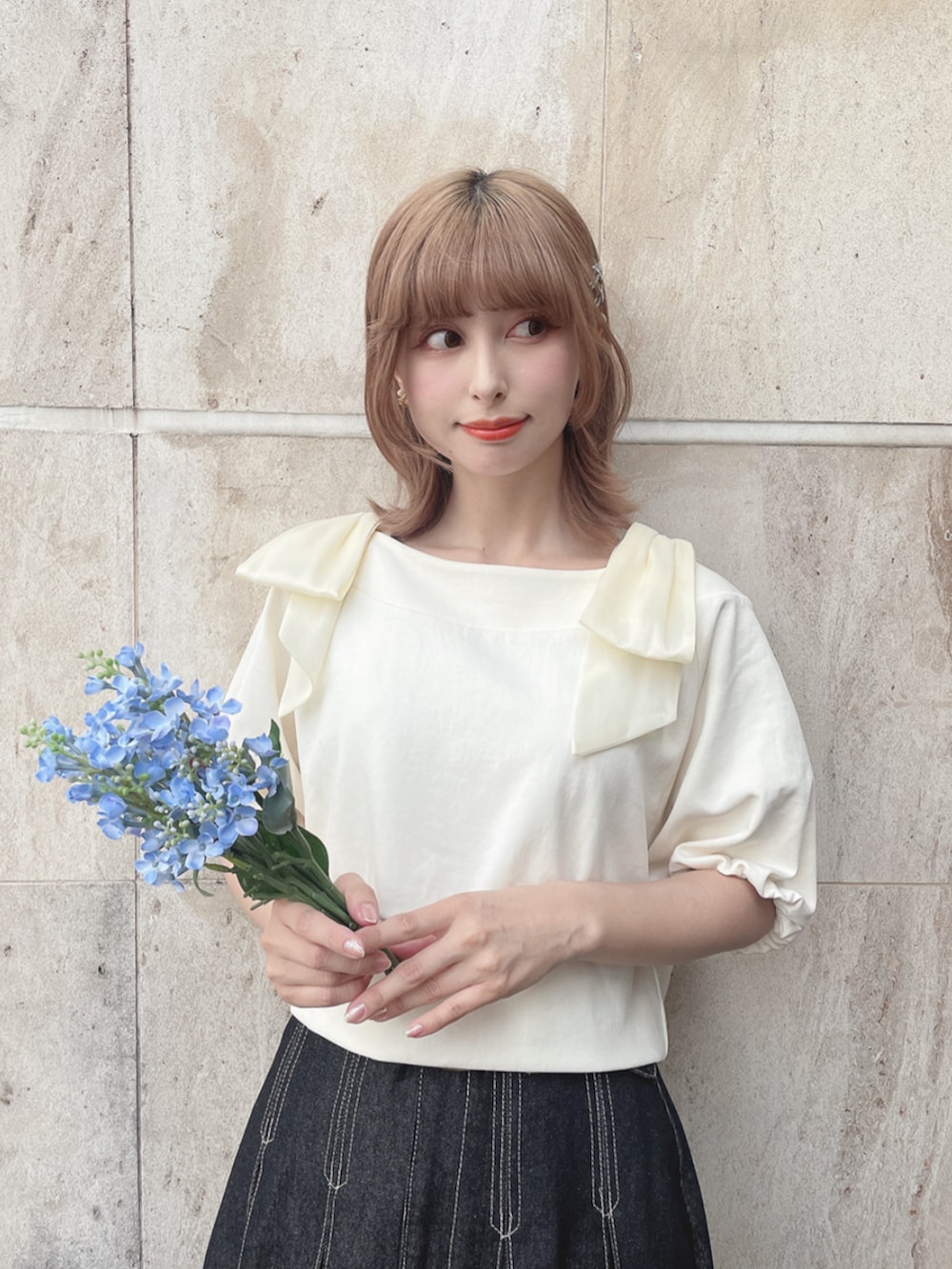 ホワイト系のスニーカー、ブラック系のデニムスカート、ホワイト系のTシャツ/カットソーを着用したレディースの春コーディネートの3枚目の写真