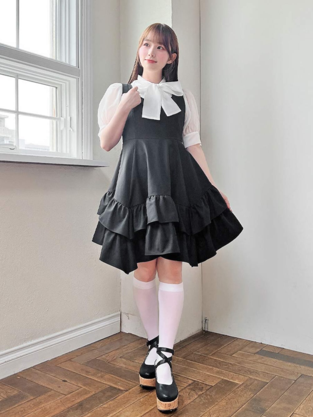 ブラック系のパンプス、ブラック系のジャンパースカート、ホワイト系のシャツ/ブラウスを着用したレディースの夏コーディネートの2枚目の写真