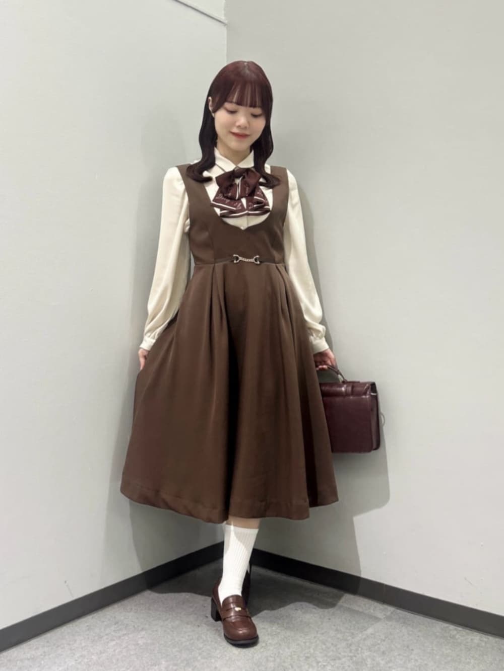 ブラウン系のジャンパースカート、ブラウン系のローファー、ブラウン系のショルダーバッグを着用したレディースの秋コーディネートの3枚目の写真