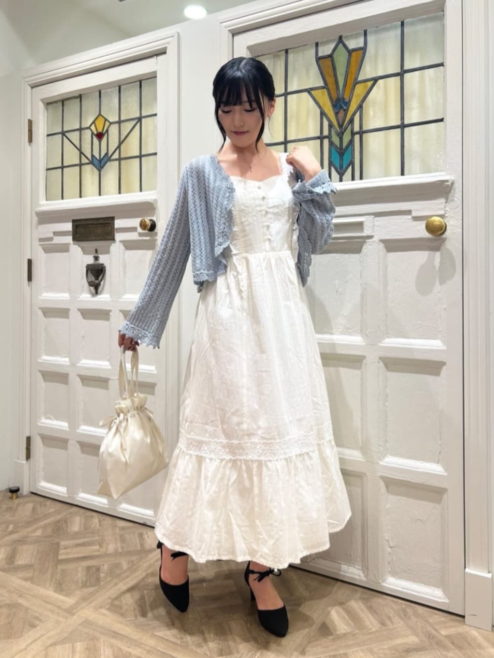 ホワイト系のワンピース、ブルー系のカーディガン/ボレロ、ブラック系のパンプスを着用したレディースの春コーディネートの2枚目の写真