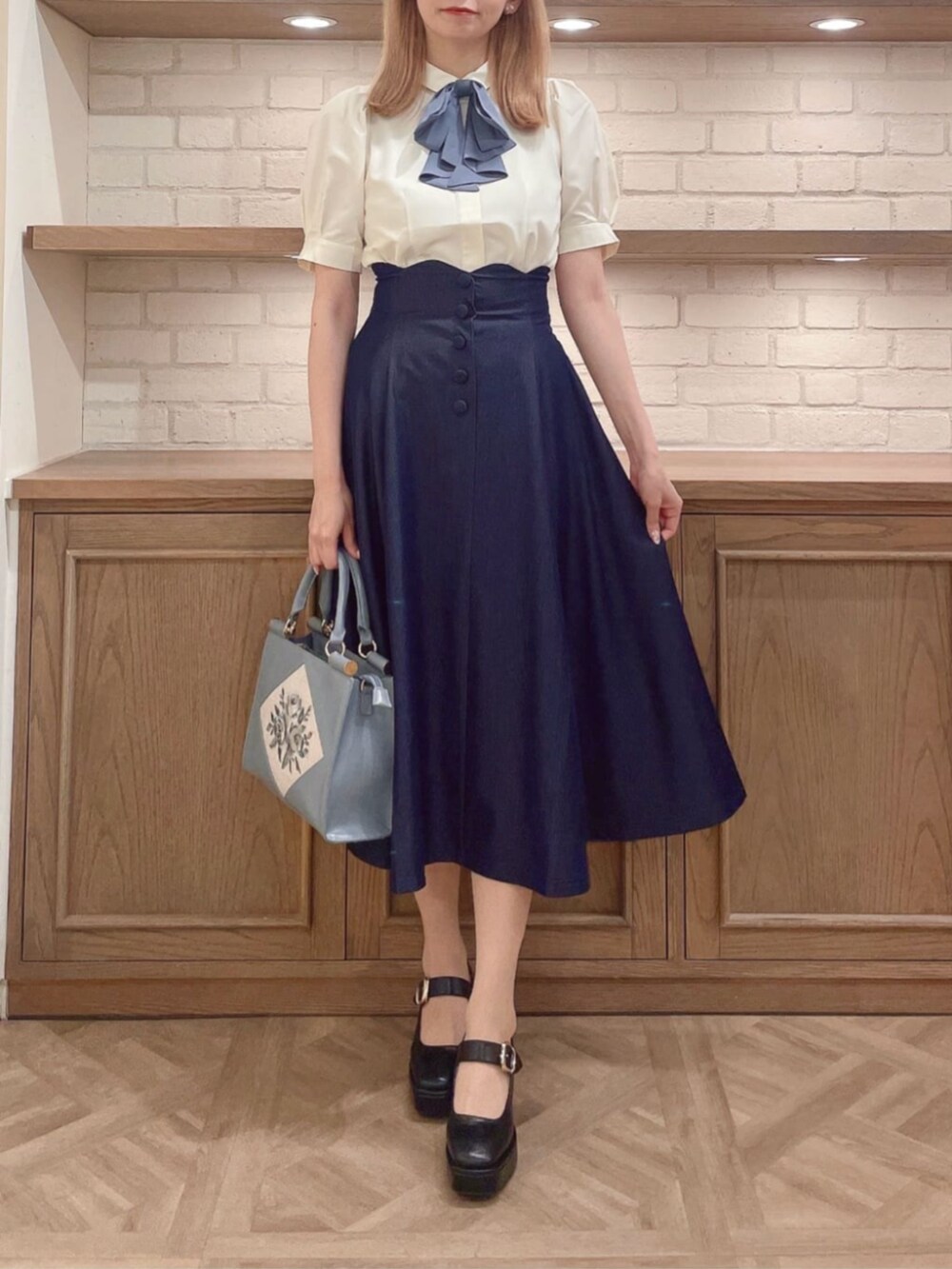 ホワイト系のシャツ/ブラウス、ブラック系のパンプス、ブルー系のトートバッグを着用したレディースの夏コーディネートの2枚目の写真