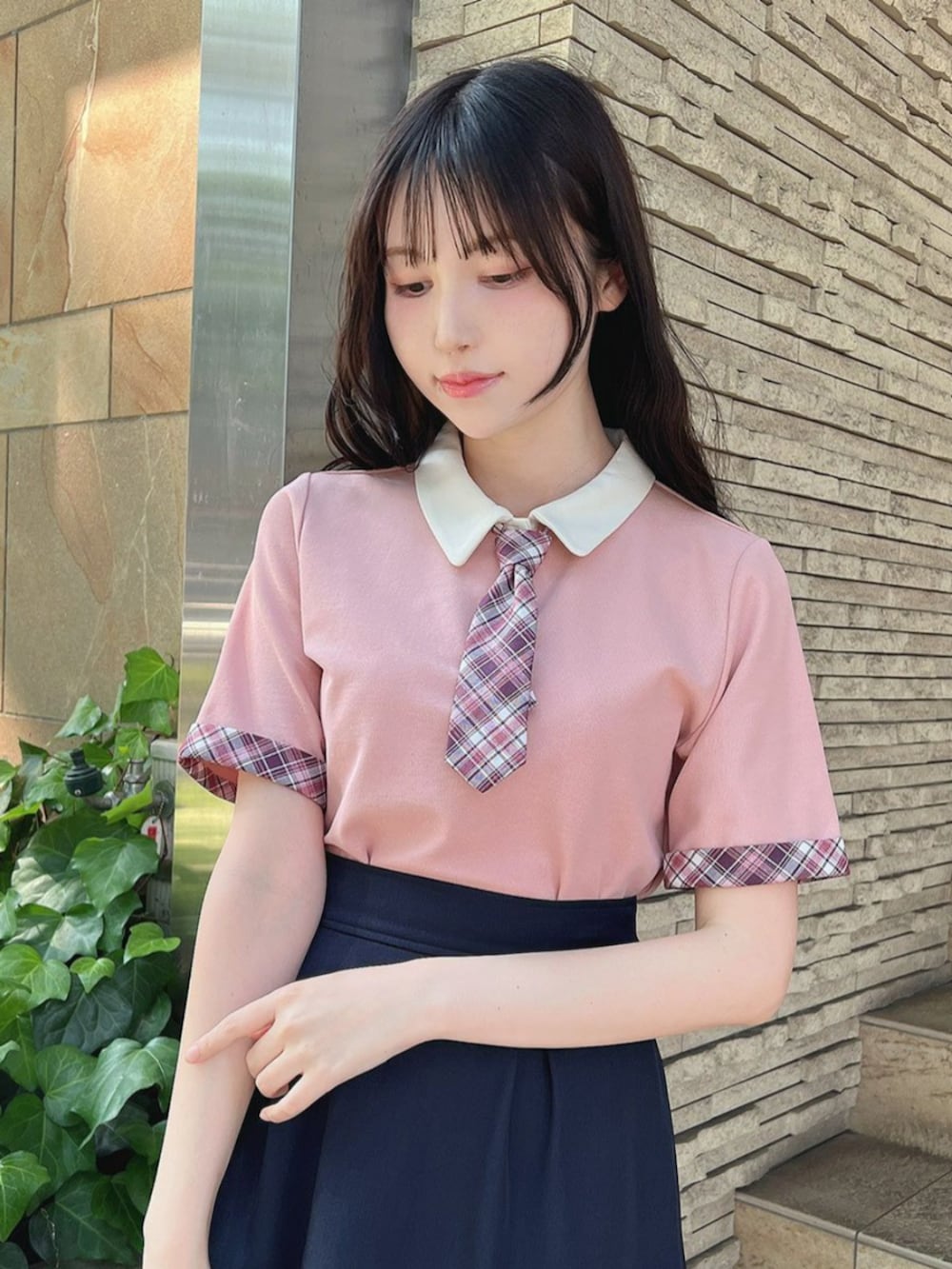 ブルー系のスカート、ブラック系のサンダル、ピンク系のポロシャツを着用したレディースの夏コーディネートの2枚目の写真