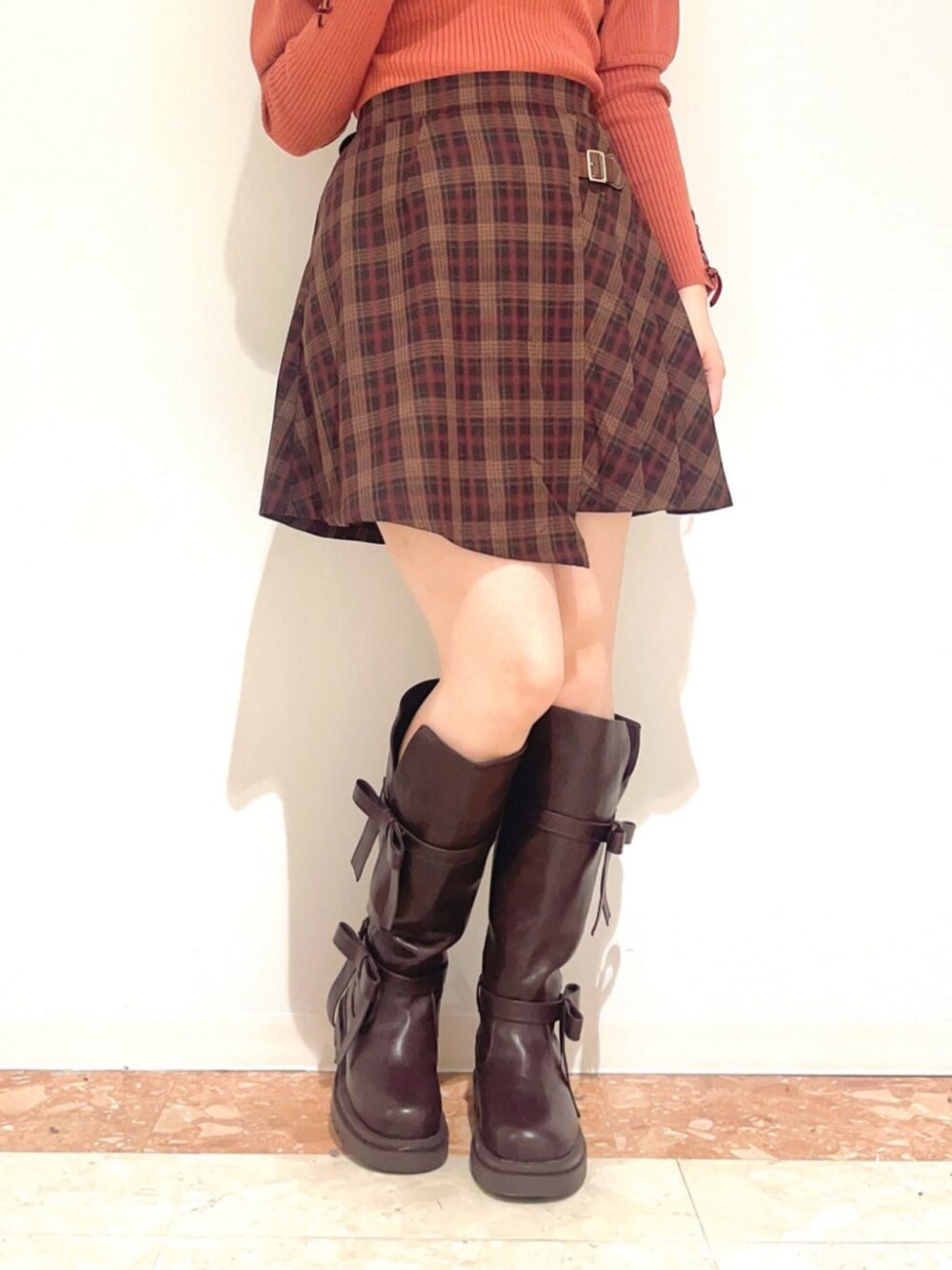 ブラウン系のブーツ、ブラウン系のスカート、オレンジ系のニット/セーターを着用したレディースの秋コーディネートの3枚目の写真