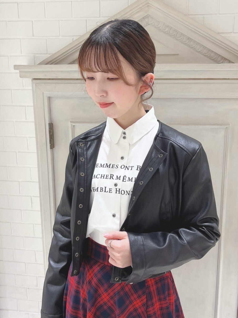 ブラック系のライダースジャケット、ホワイト系のシャツ/ブラウス、レッド系のスカートを着用したレディースの冬コーディネートの2枚目の写真