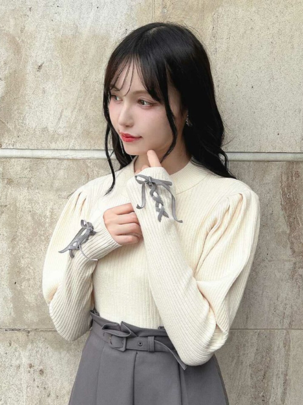 ブラック系のパンプス、グレー系のスカート、ホワイト系のニット/セーターを着用したレディースの秋コーディネートの2枚目の写真