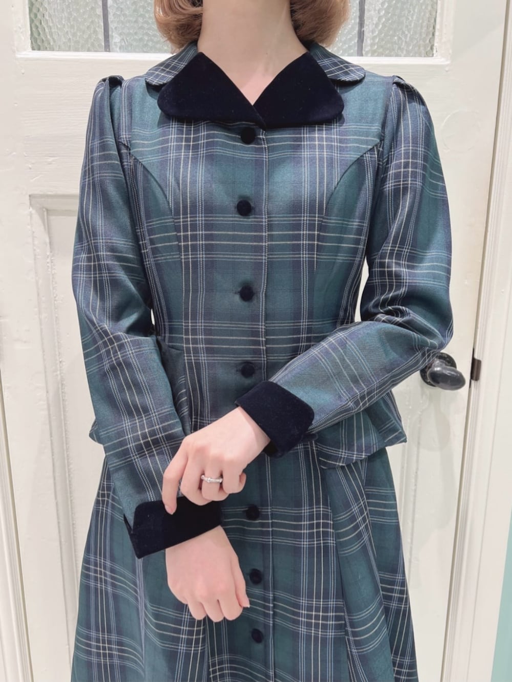 ブルー系のハンドバッグ、ブラック系のパンプス、グリーン系のワンピースを着用したレディースの秋コーディネートの2枚目の写真