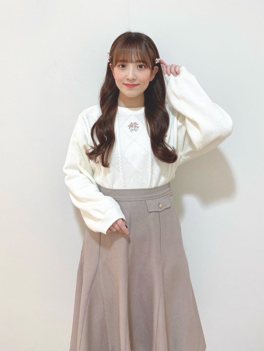 ピンク系のスカート、ブラウン系のパンプス、ホワイト系のニット/セーターを着用したレディースの冬コーディネートの2枚目の写真