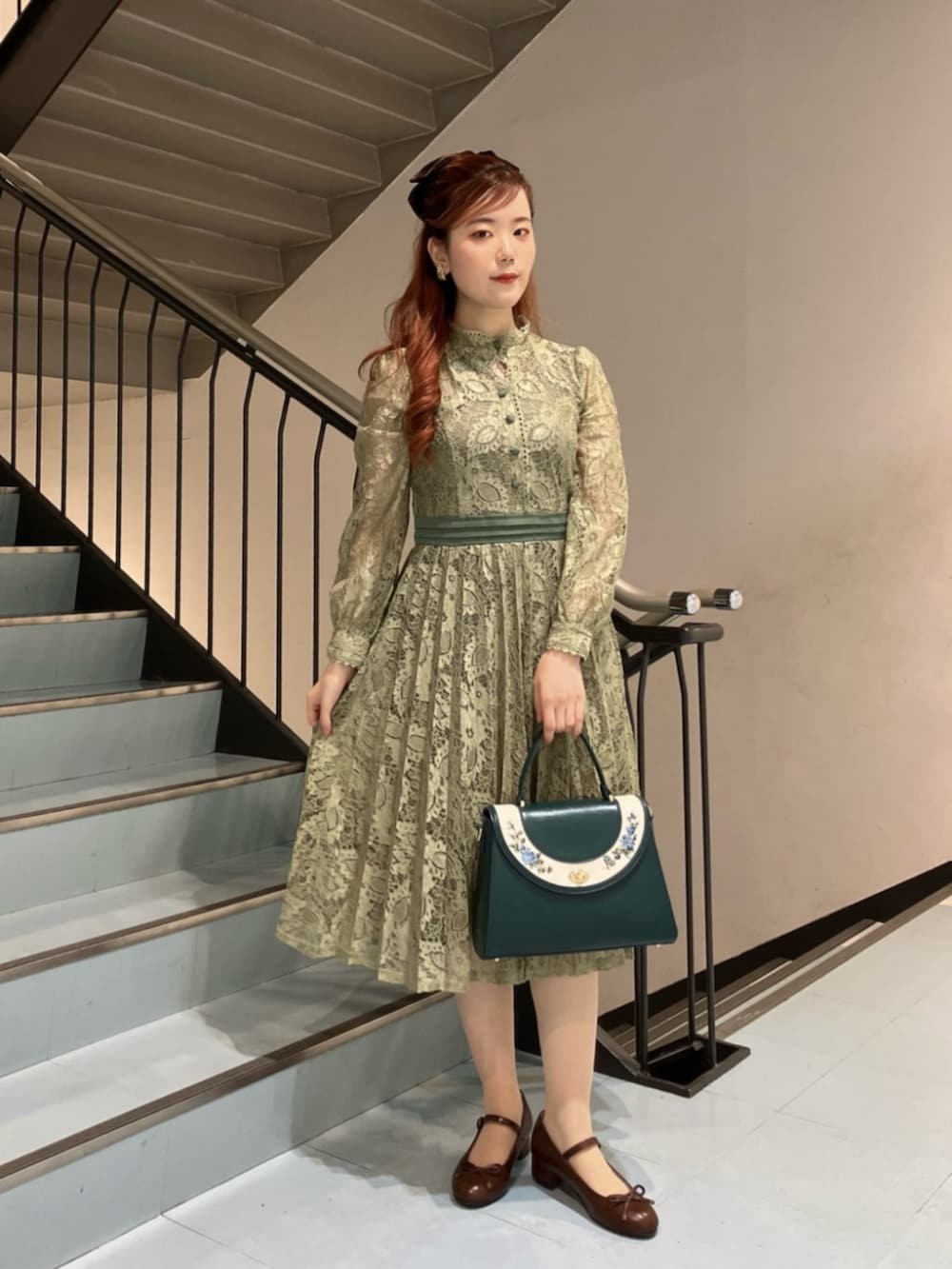 ブルー系のハンドバッグ、ブラウン系のバレエシューズ、グリーン系のドレスを着用したレディースの冬コーディネートの2枚目の写真