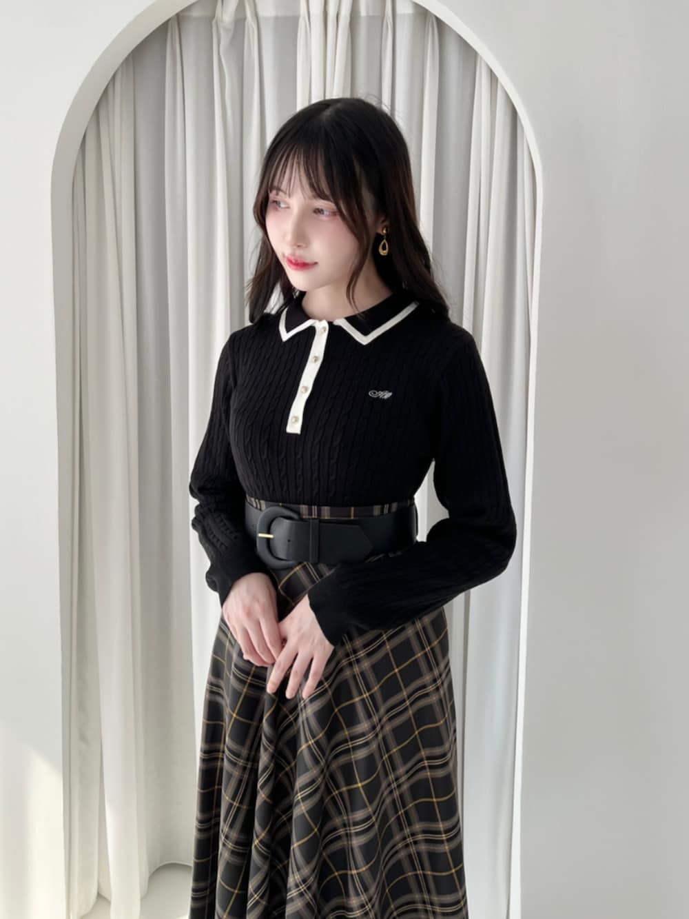 ブラック系のパンプス、ブラック系のスカート、ブラック系のニット/セーターを着用したレディースの秋コーディネートの2枚目の写真