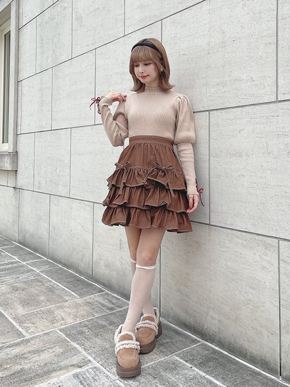 ブラウン系のスカート、ベージュ系のニット/セーター、ブラック系のカチューシャを着用したレディースの秋コーディネートの2枚目の写真