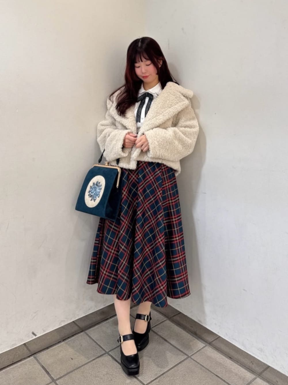 ブラック系のパンプス、ホワイト系のその他アウター、ブルー系のハンドバッグを着用したレディースの冬コーディネートの2枚目の写真