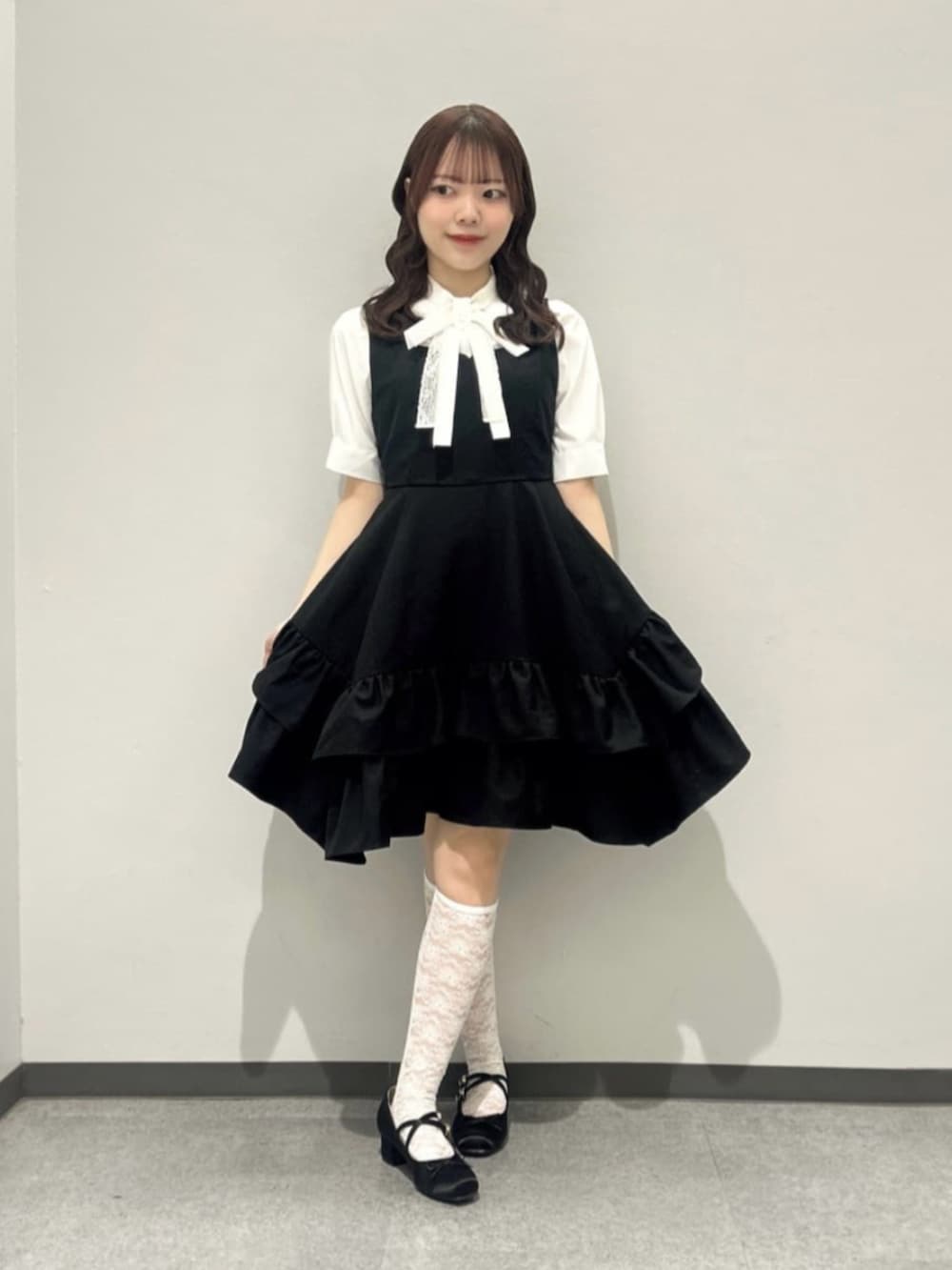 ブラック系のパンプス、ホワイト系のシャツ/ブラウス、ブラック系のジャンパースカートを着用したレディースの春コーディネートの2枚目の写真