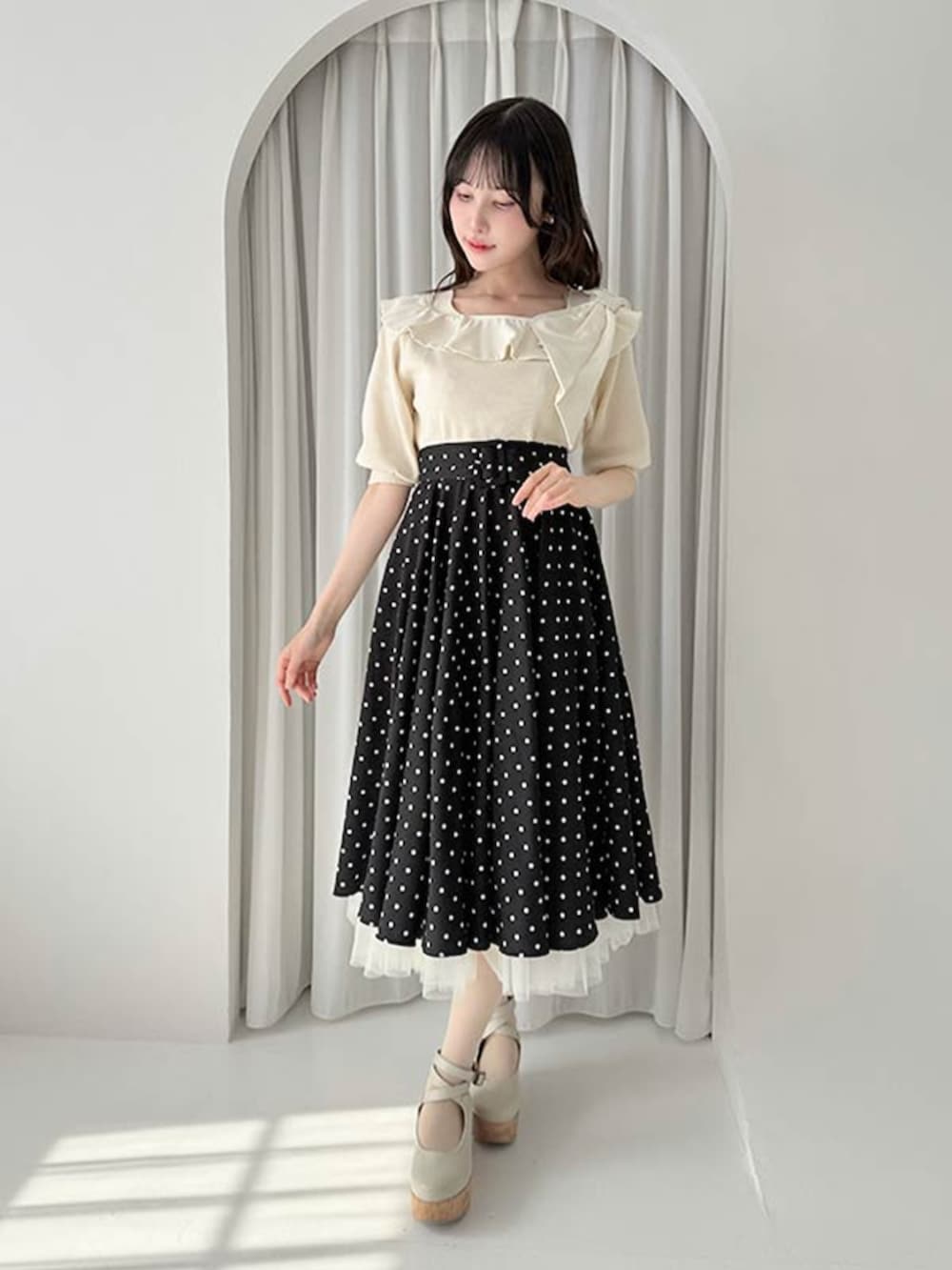 ホワイト系のパンプス、ブラック系のスカート、ホワイト系のニット/セーターを着用したレディースの夏コーディネートの2枚目の写真