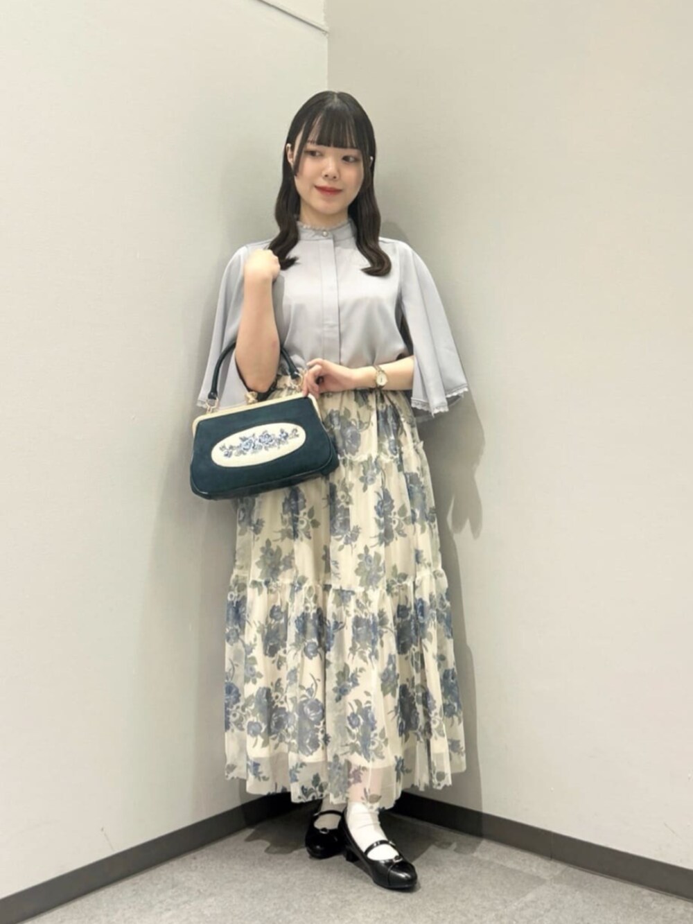 グレー系のシャツ/ブラウス、ブルー系のスカート、ブルー系のハンドバッグを着用したレディースの夏コーディネートの2枚目の写真