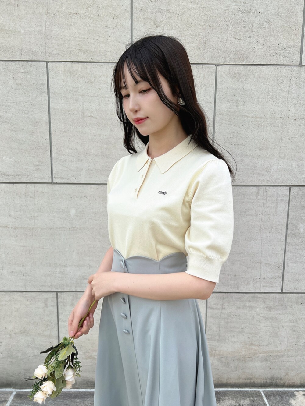 ブラウン系のローファー、グリーン系のスカート、ホワイト系のポロシャツを着用したレディースの春コーディネートの2枚目の写真