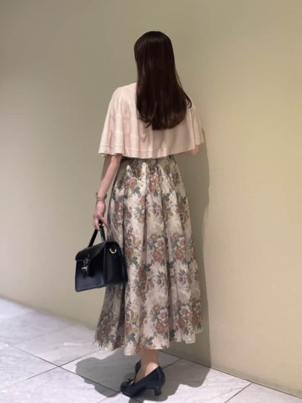 ブラック系のハンドバッグ、ブラック系のパンプス、ベージュ系のスカートを着用したレディースの秋コーディネートの3枚目の写真