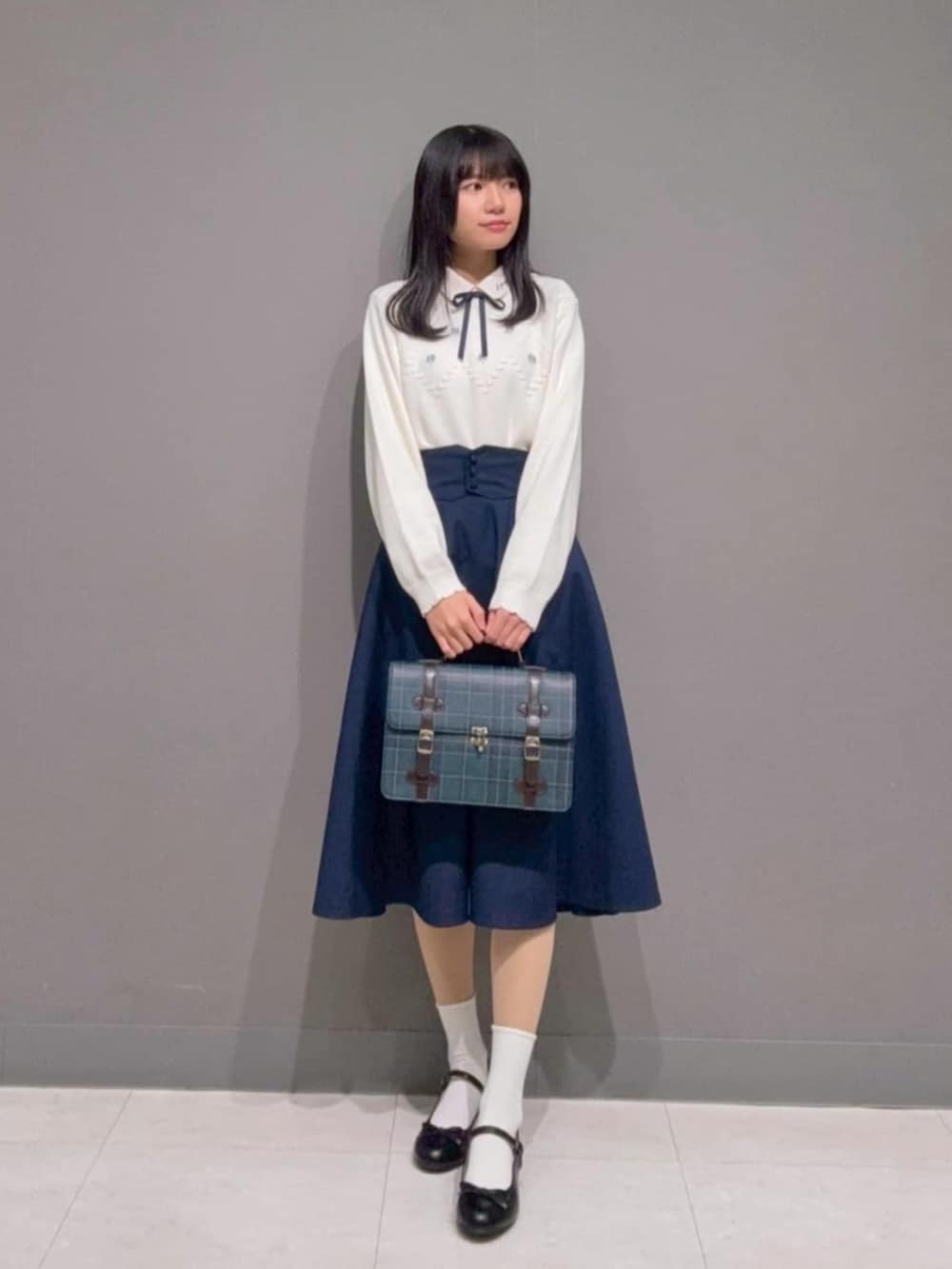 ブルー系のショルダーバッグ、ブルー系のスカート、ブラック系のバレエシューズを着用したレディースの冬コーディネートの2枚目の写真