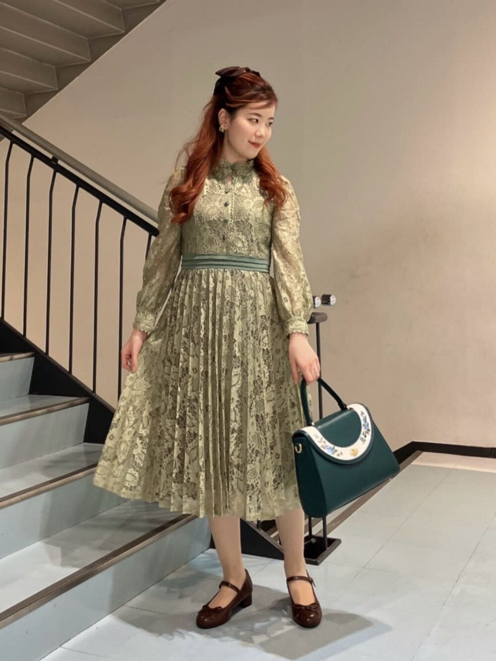 ブルー系のハンドバッグ、ブラウン系のバレエシューズ、グリーン系のドレスを着用したレディースの冬コーディネートの5枚目の写真