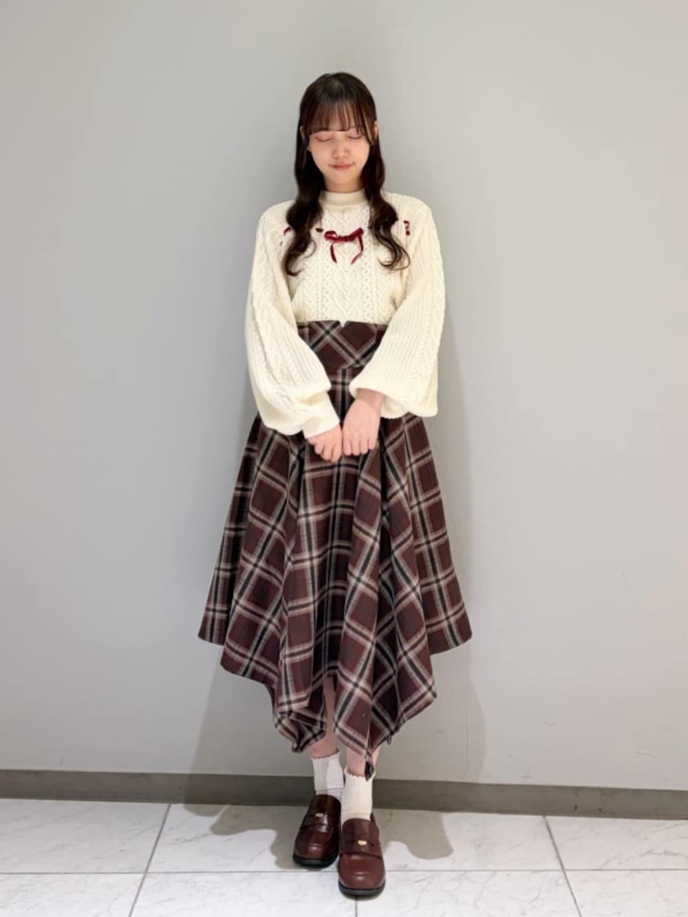 ブラウン系のローファー、ホワイト系のニット/セーター、ブラウン系のダウンジャケット/コートを着用したレディースの冬コーディネートの2枚目の写真