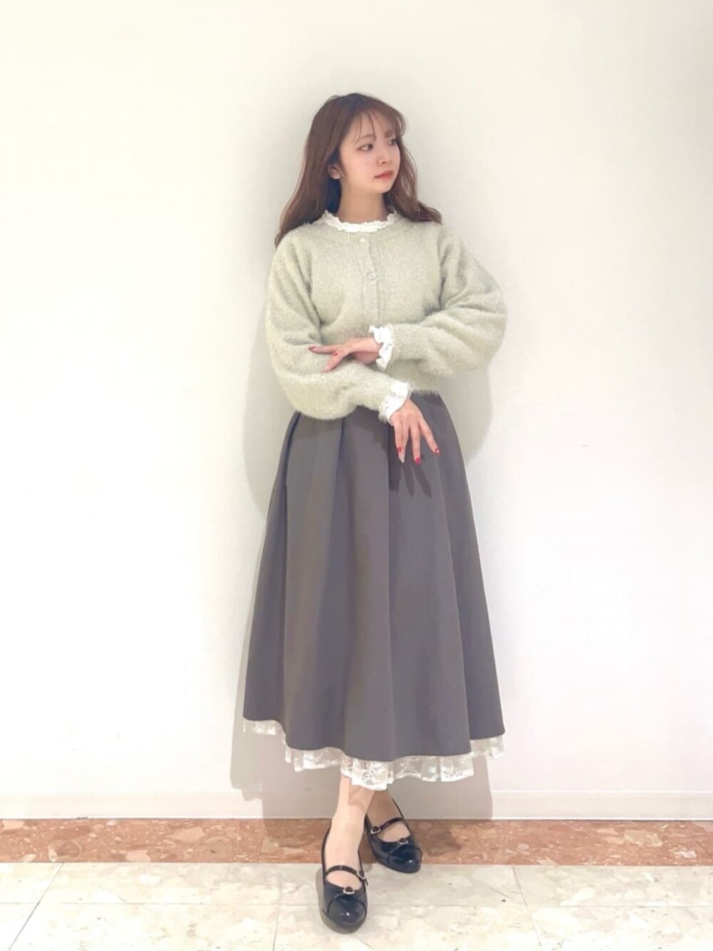 ブラック系のパンプス、ホワイト系のカーディガン/ボレロ、グレー系のスカートを着用したレディースの秋コーディネートの2枚目の写真