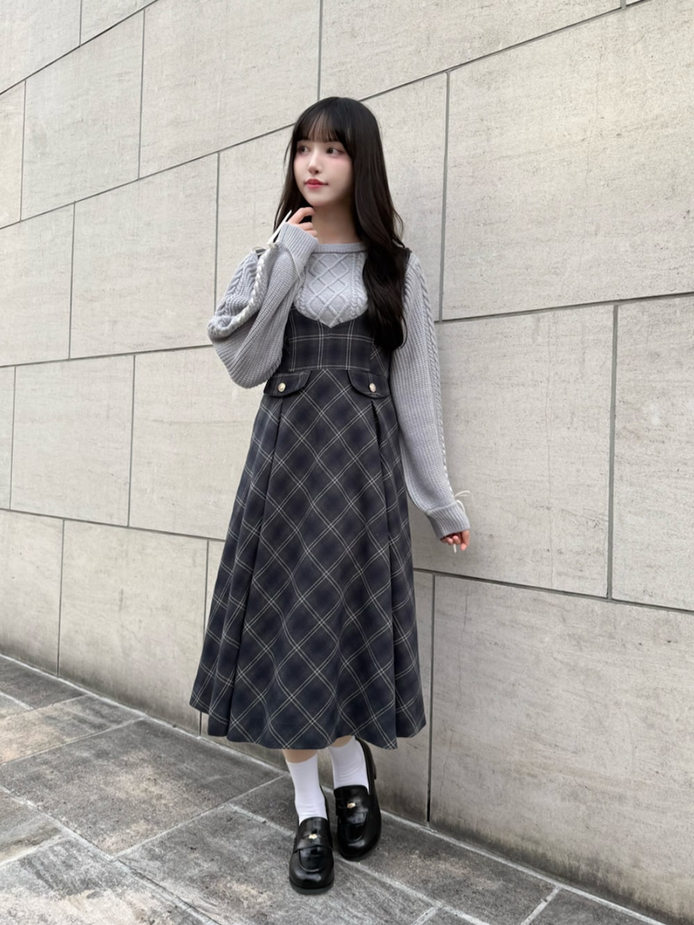 ブラック系のローファー、グレー系のニット/セーター、ブルー系のジャンパースカートを着用したレディースの冬コーディネートの2枚目の写真