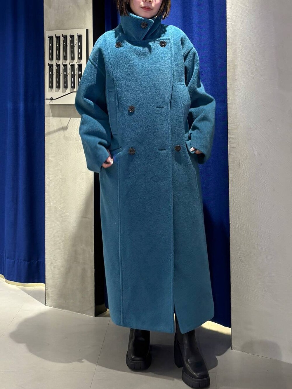 グリーン系のチェスターコート、ブラック系のブーツ、グレー系のニット/セーターを着用したレディースの冬コーディネートの7枚目の写真