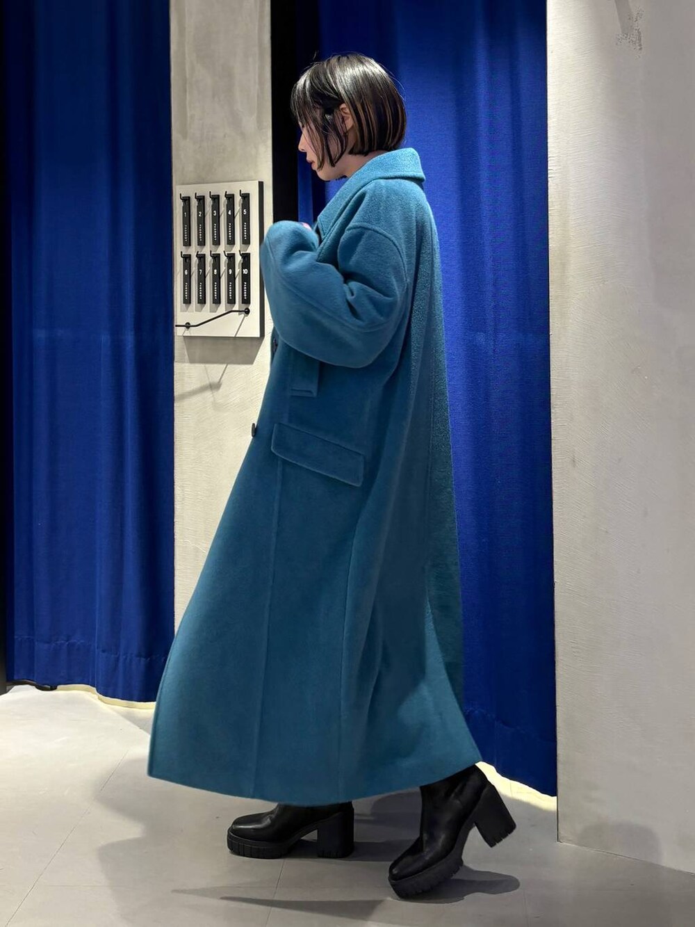 グリーン系のチェスターコート、ブラック系のブーツ、グレー系のニット/セーターを着用したレディースの冬コーディネートの4枚目の写真