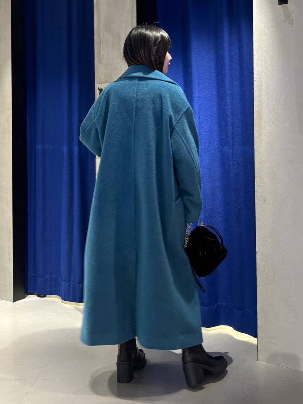 グリーン系のチェスターコート、ブラック系のブーツ、グレー系のニット/セーターを着用したレディースの冬コーディネートの5枚目の写真