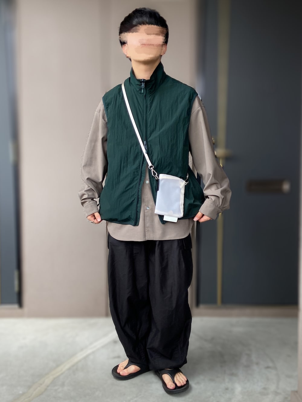 ブラック系のサンダル、ブラック系のパンツ、グリーン系のベストを着用したメンズの秋コーディネートの2枚目の写真