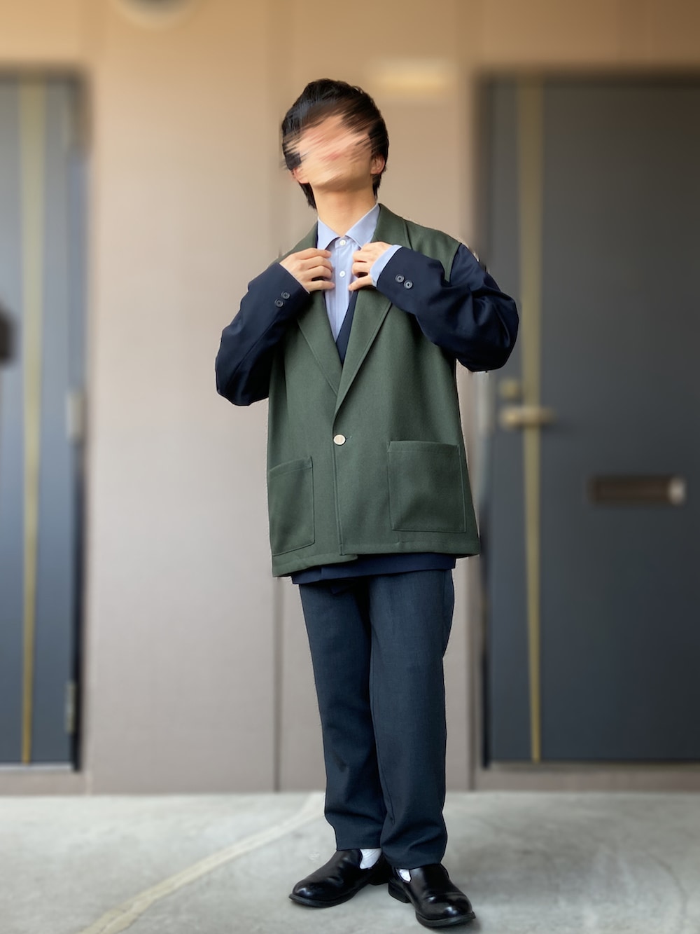 ブラック系のスリッポン、ブルー系のテーラードジャケット、グリーン系のベストを着用したメンズの春コーディネートの2枚目の写真