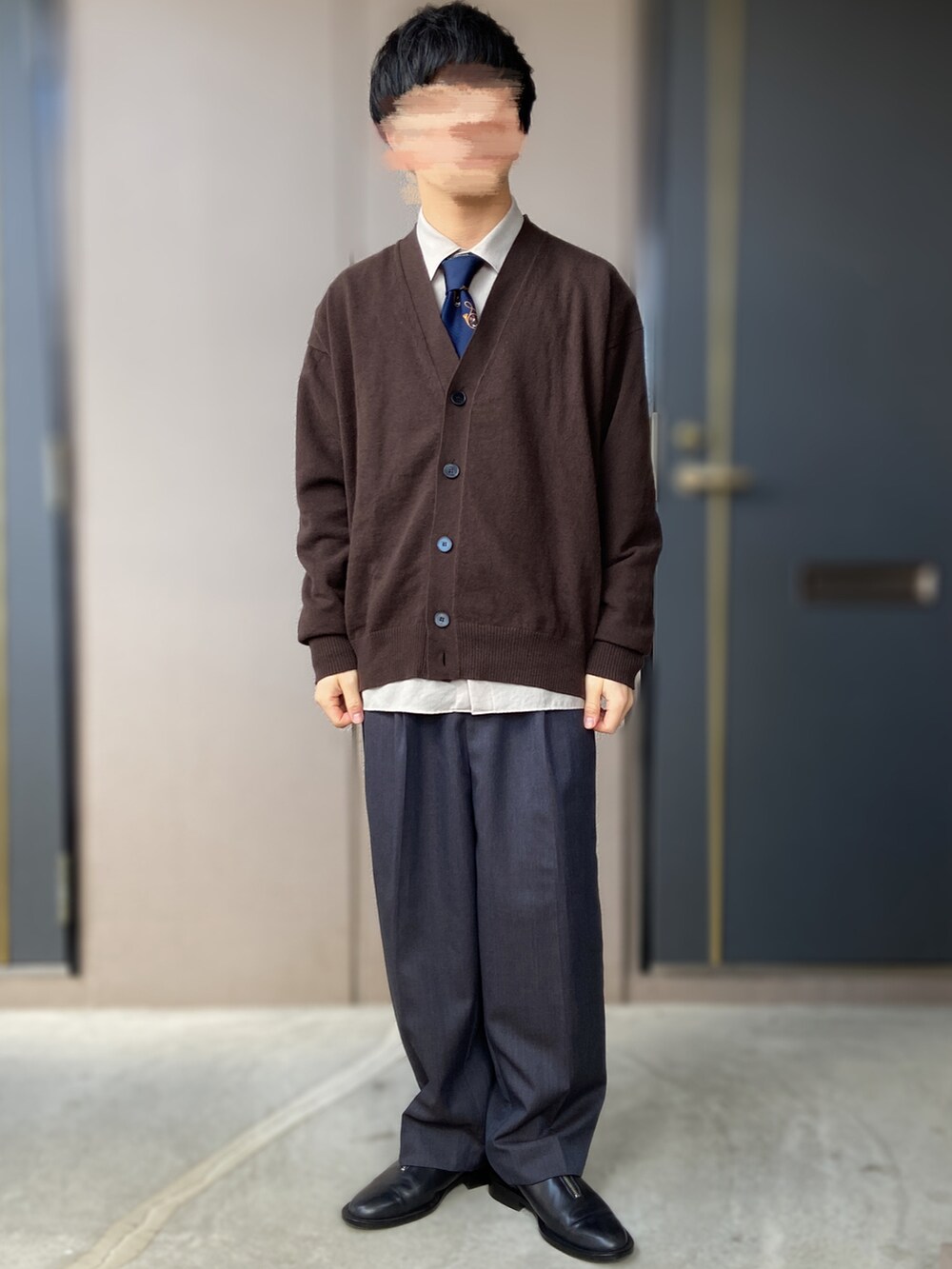 ブルー系のスラックス、ブラック系のドレスシューズ、ブラック系のカバーオールを着用したメンズの春コーディネートの4枚目の写真