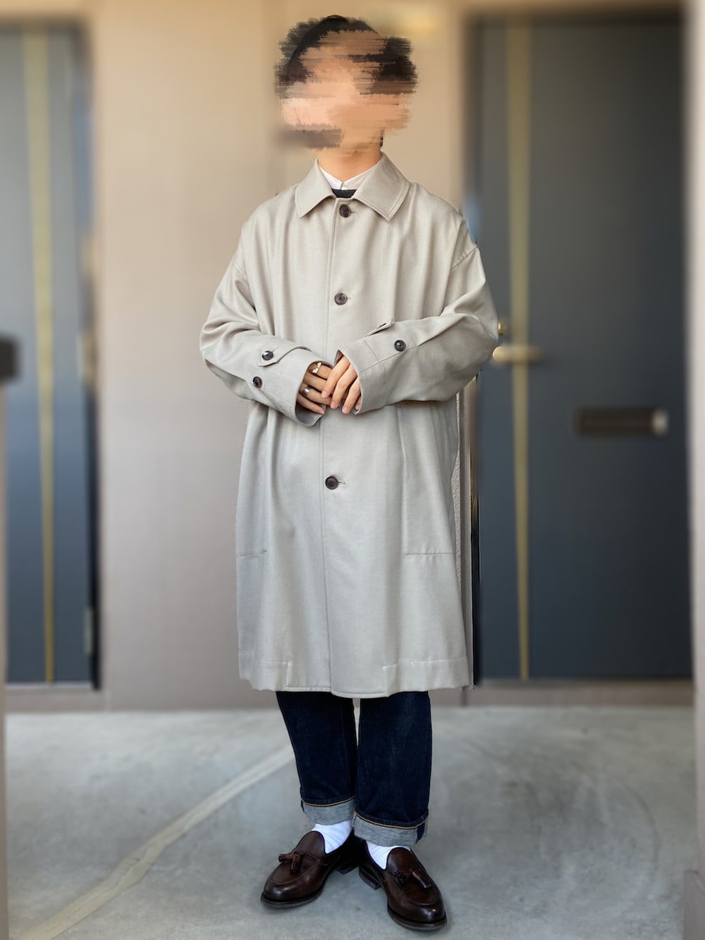 ブラウン系のローファー、ブルー系のデニムパンツ、グレー系のステンカラーコートを着用したメンズの冬コーディネートの2枚目の写真