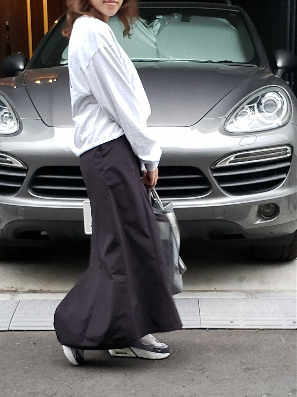 グレー系のTシャツ/カットソー、ブラック系のスカート、グレー系のショルダーバッグを着用したレディースの春コーディネートの2枚目の写真