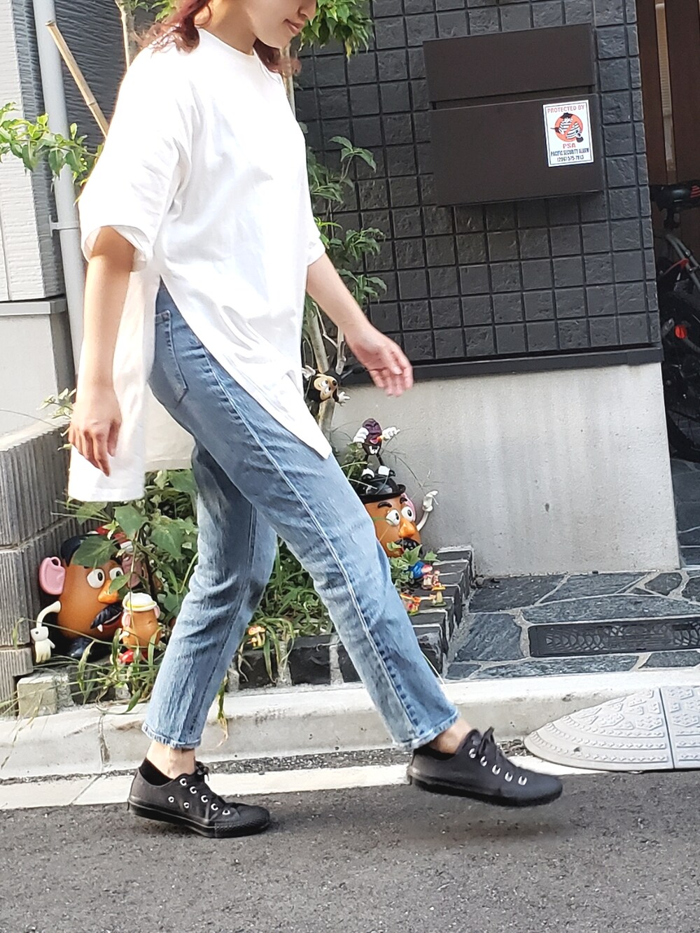 ホワイト系のTシャツ/カットソー、グレー系のスニーカー、ブルー系のデニムパンツを着用したレディースの秋コーディネートの4枚目の写真