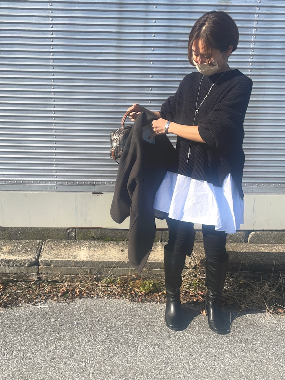 ブラウン系のショルダーバッグ、シルバー系のネックレスを着用したレディースの冬コーディネートの2枚目の写真