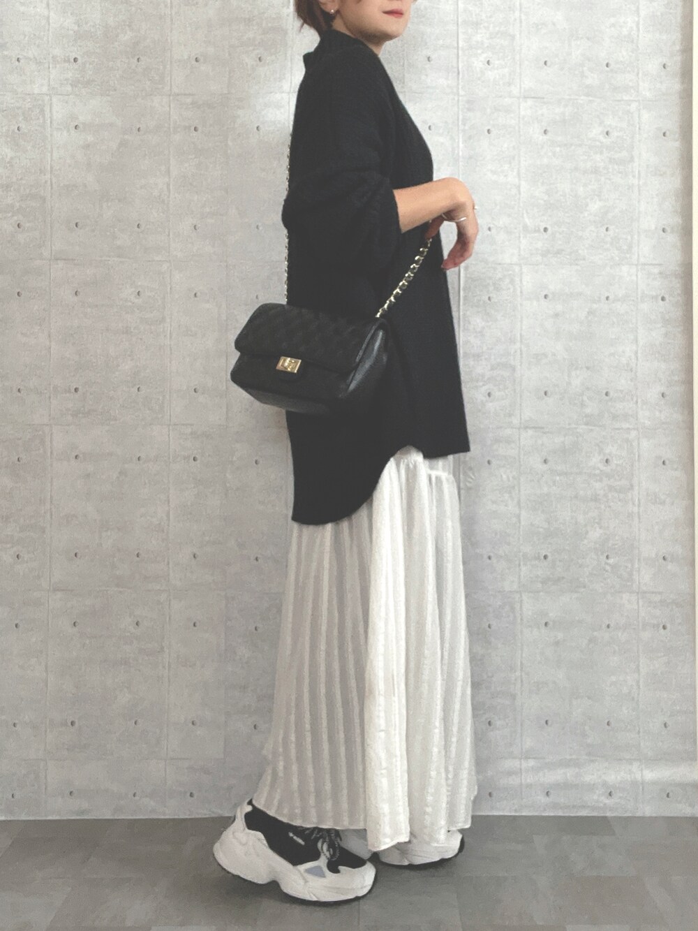 ホワイト系のワンピース、ブラック系のニット/セーター、ブラック系のスニーカーを着用したレディースの冬コーディネートの2枚目の写真