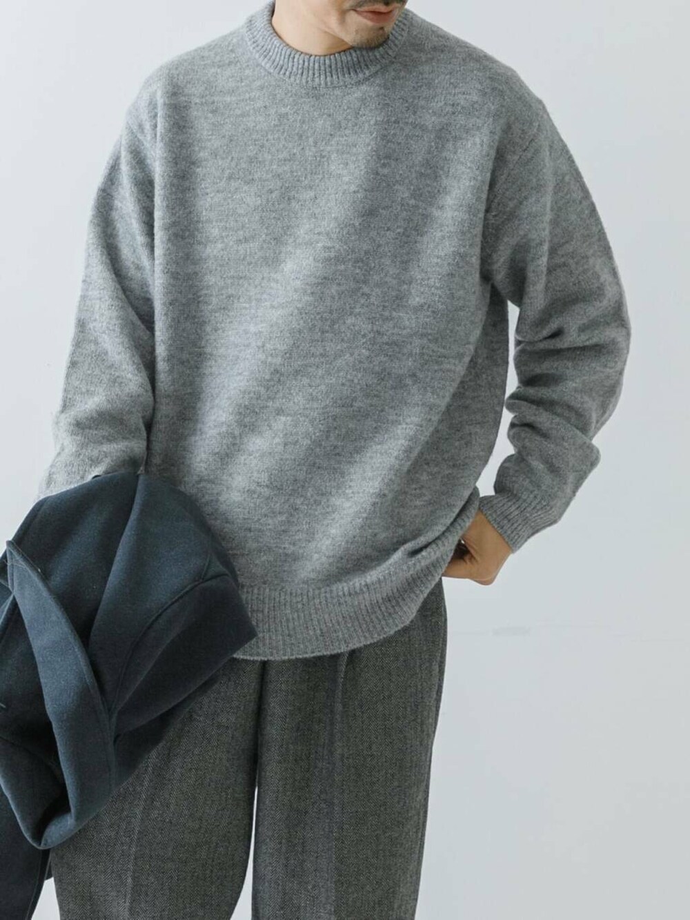 ブルー系のステンカラーコート、グレー系のニット/セーター、グレー系のスラックスを着用したメンズの冬コーディネートの4枚目の写真