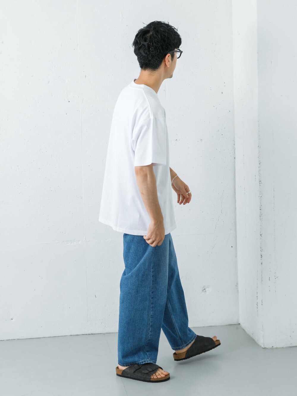 ブルー系のデニムパンツ、グレー系のサンダル、ホワイト系のTシャツ/カットソーを着用したメンズの夏コーディネートの7枚目の写真