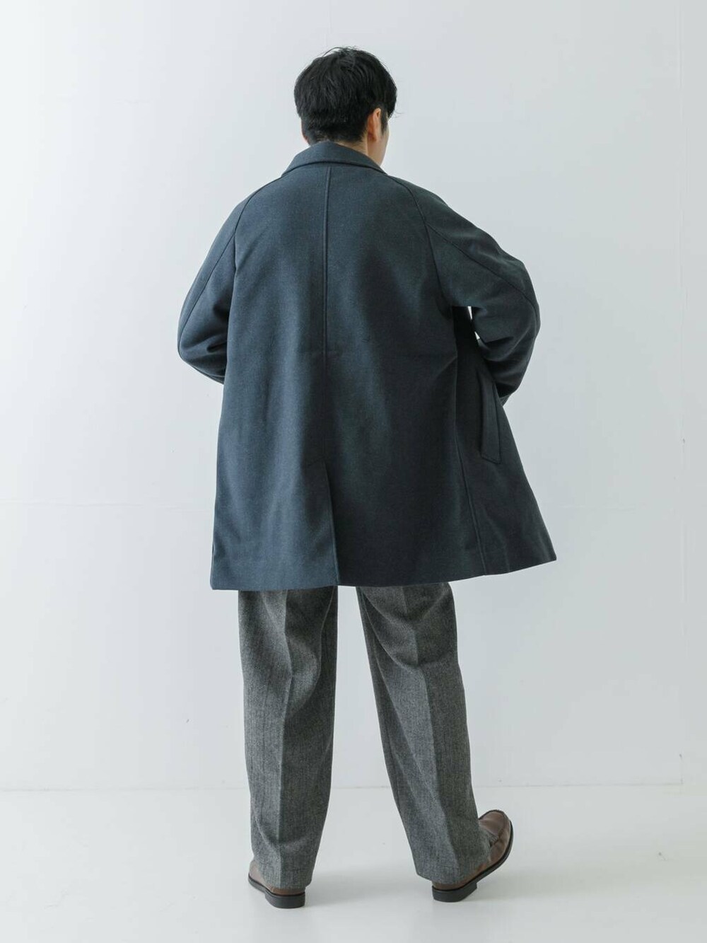 ブルー系のステンカラーコート、グレー系のニット/セーター、グレー系のスラックスを着用したメンズの冬コーディネートの6枚目の写真