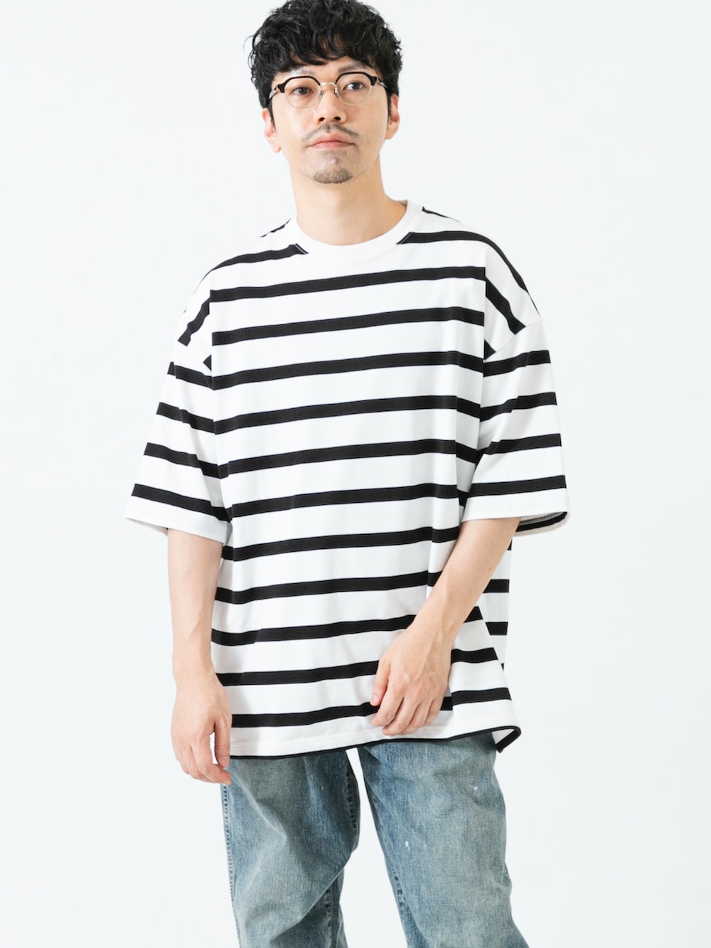 ブラック系のスニーカー、ホワイト系のTシャツ/カットソー、ブルー系のデニムパンツを着用したメンズの夏コーディネートの2枚目の写真