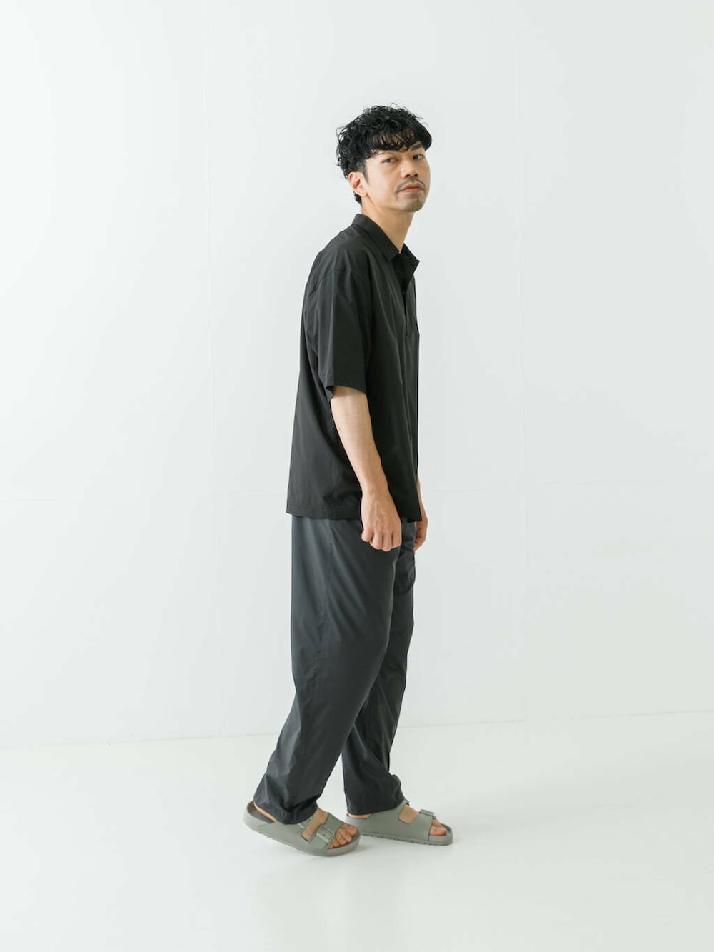 グレー系のサンダル、ブラック系のポロシャツ、グレー系のその他パンツを着用したメンズの夏コーディネートの5枚目の写真